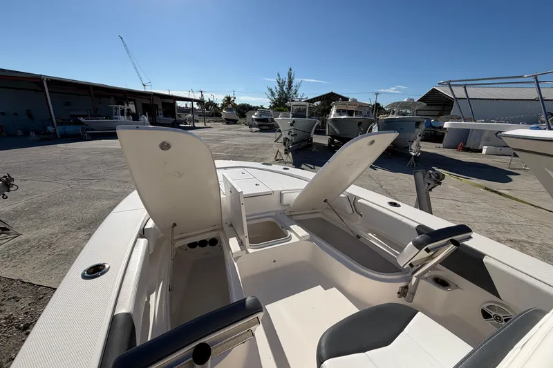 Slide: The Image of 2020 Robalo 246 Cayman SD boat with open storage compartments in a marina setting. - 16
