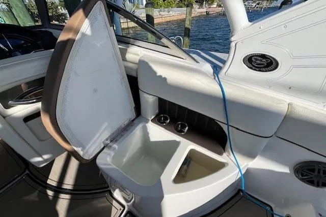 Slide: The Image of 2019 Cobalt 25SC boat interior with white and brown seating, cup holders, and speaker. - 12