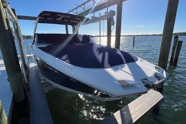 Slide: The Image of 2019 Cobalt 25SC boat docked, covered, with sleek design and modern features. - 2