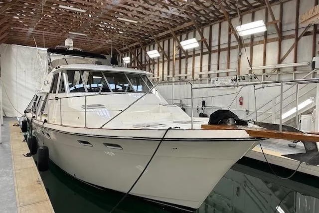 Slide: The Image of 1985 Bayliner 4550 Motoryacht docked with American flag, marina background. - 146