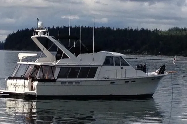 Slide: The Image of 1985 Bayliner 4550 Motoryacht on calm water with forested shoreline in background. - 154