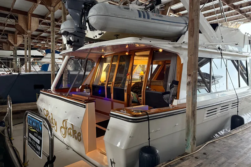 Slide: The Image of 1985 Bayliner 4550 Motoryacht on serene water, surrounded by lush forest. - 3