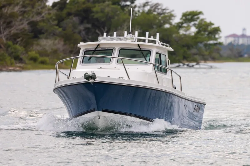 Slide: The Image of Manufacturer Provided Image: 2026 Parker 227 Explorer boat cruising on a calm waterway, surrounded by lush greenery. - 2
