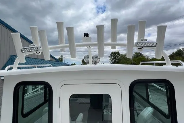 Slide: The Image of 2026 Parker 247 Explorer boat with rod holders and LED lights under cloudy sky. - 16