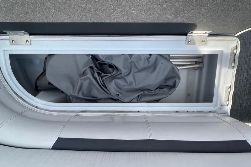 Slide: The Image of Storage compartment in 2023 Godfrey Sweetwater 2086 SB boat, containing folded fabric and metal poles. - 24