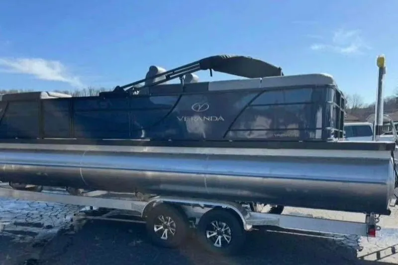 Slide: The Image of 2025 Veranda Relax VR25RC pontoon boat on trailer under clear blue sky. - 5