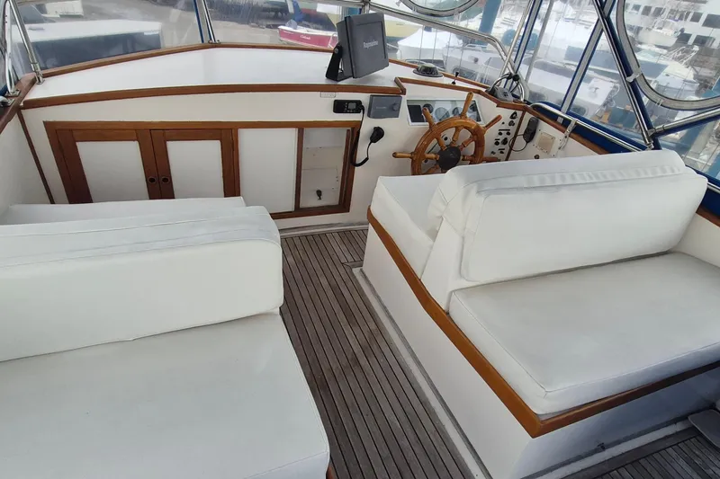 Slide: The Image of 1983 Grand Banks 42 Classic yacht helm with wooden wheel and white seating. - 43