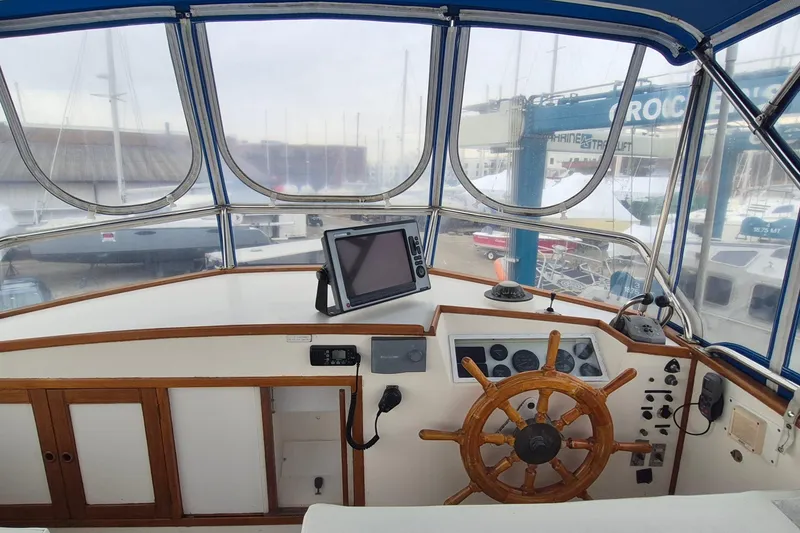 Slide: The Image of 1983 Grand Banks 42 Classic yacht interior with wooden helm and white seating. - 44
