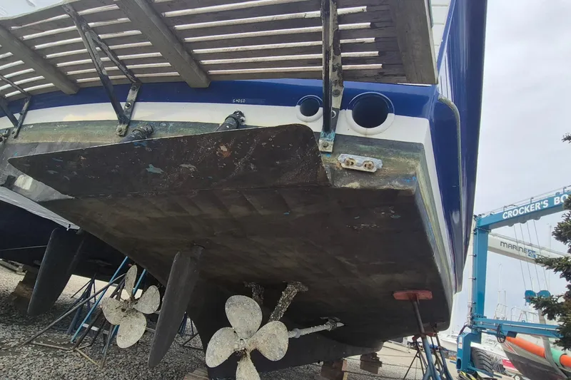 Slide: The Image of 1983 Grand Banks 42 Classic boat hull on gravel, showing wear and blue paint remnants. - 75