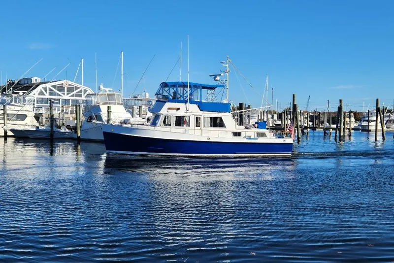 Slide: The Image of 1983 Grand Banks 42 Classic yacht cruising in a marina under clear blue skies. - 80
