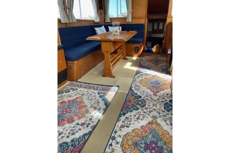 Slide: The Image of 1983 Grand Banks 42 Classic interior with wooden helm, colorful rugs, and dining table. - 9