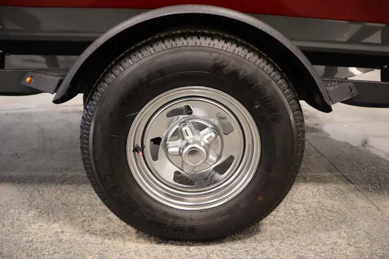 Slide: The Image of 2024 Tracker Pro Guide V-16 WT trailer tire with chrome wheel on concrete surface. - 50