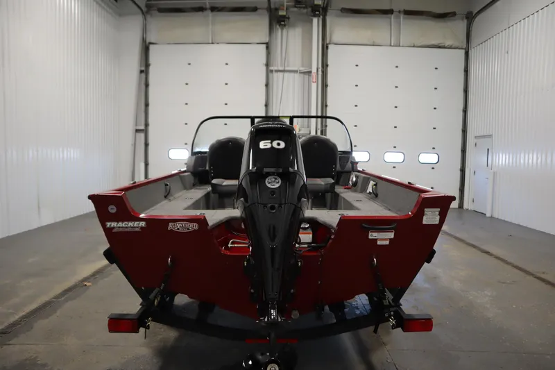 Slide: The Image of 2024 Tracker Pro Guide V-16 WT boat in a garage, rear view with motor. - 6