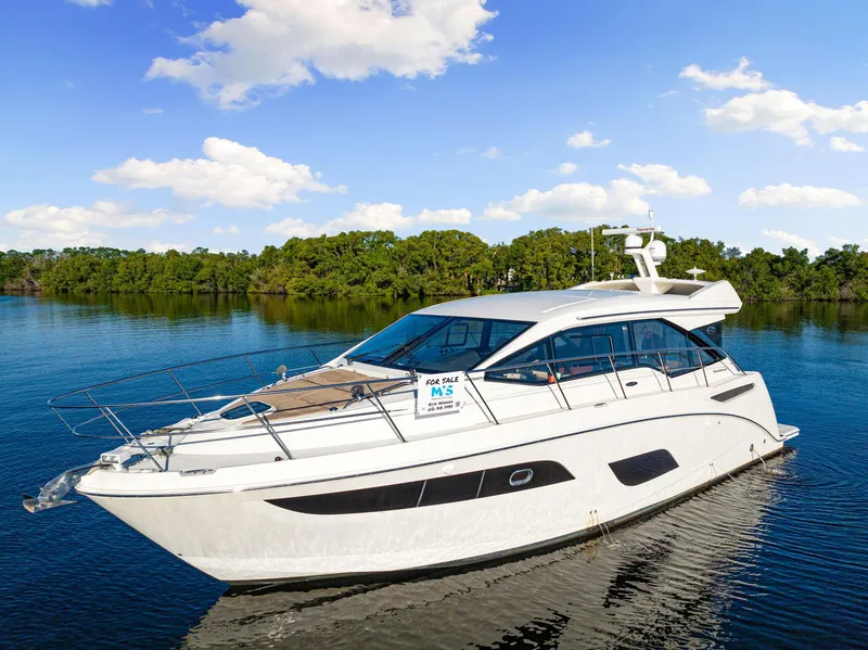 The Image of 2017 Sea Ray 460 Sundancer yacht on serene water, clear sky background. - 0