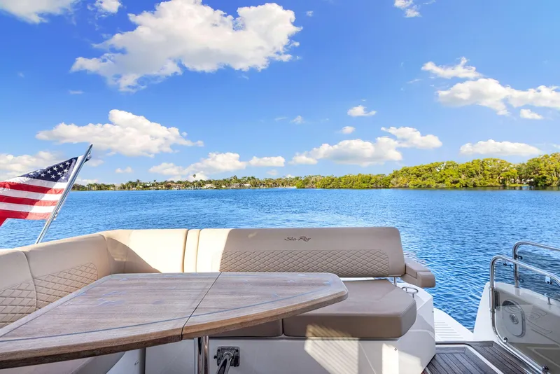 Slide: The Image of 2017 Sea Ray 460 Sundancer yacht with seating area, table, and American flag on a sunny day. - 22