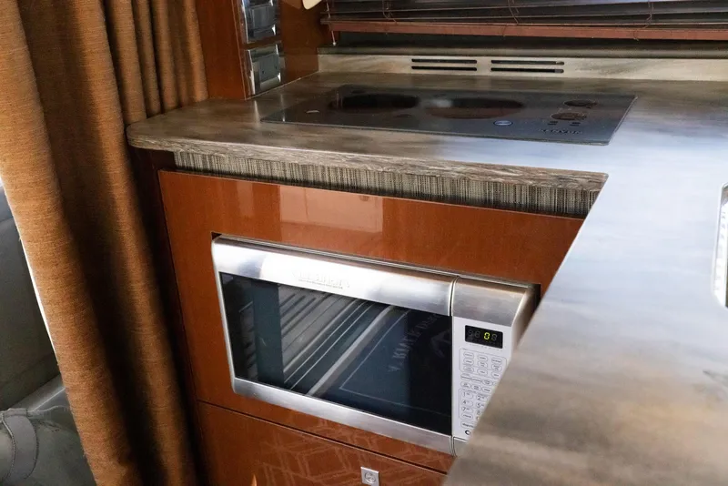 Slide: The Image of 2017 Sea Ray 460 Sundancer kitchen with microwave and stovetop. - 53