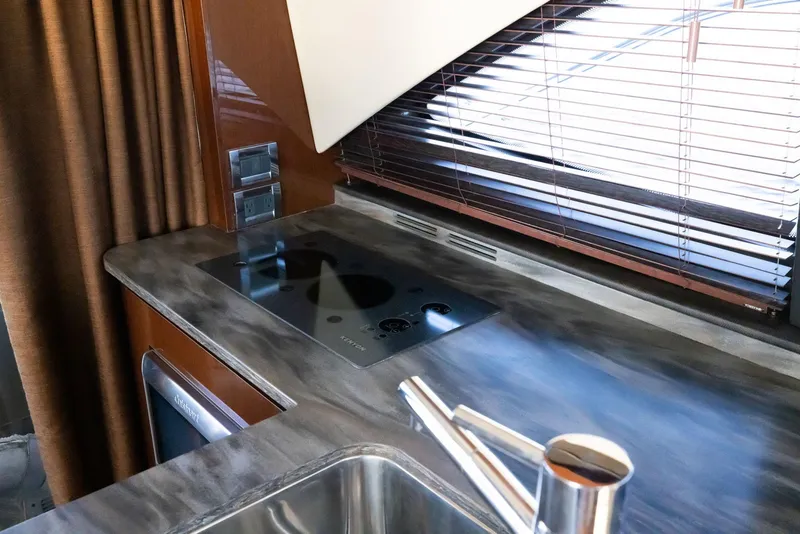 Slide: The Image of 2017 Sea Ray 460 Sundancer kitchen with modern stovetop and sleek countertop design. - 56