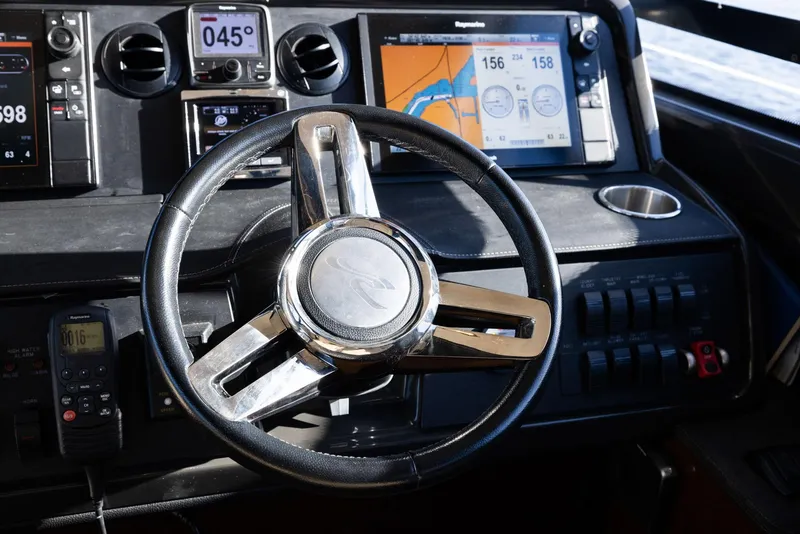 Slide: The Image of Steering wheel and dashboard of 2017 Sea Ray 460 Sundancer boat, featuring navigation displays. - 76