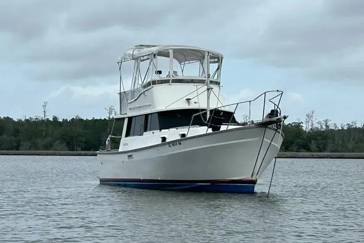 Slide: The Image of 1979 Mainship 34 Trawler anchored on calm water under cloudy skies. - 2