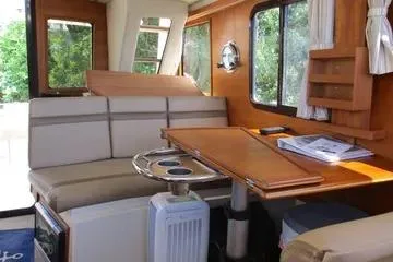 Slide: The Image of 2021 Ranger Tugs R-31 CB interior with wooden table, seating, and windows. - 11