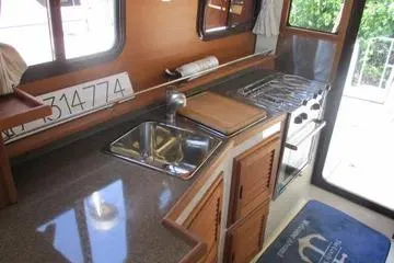 Slide: The Image of 2021 Ranger Tugs R-31 CB kitchen interior with sink, stove, and wooden cabinetry. - 14