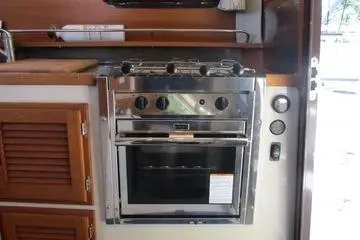 Slide: The Image of 2021 Ranger Tugs R-31 CB kitchen with stainless steel oven and wooden cabinetry. - 15