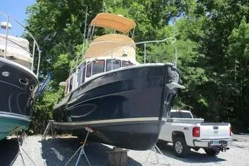 Slide: The Image of 2021 Ranger Tugs R-31 CB boat on stands, surrounded by trees and a truck. - 2