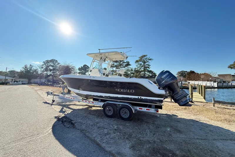 Slide: The Image of 2008 Robalo R240 Center Console boat on trailer by waterfront under clear sky. - 1