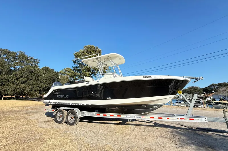 Slide: The Image of 2008 Robalo R240 Center Console boat on trailer, parked outdoors under clear blue sky. - 2