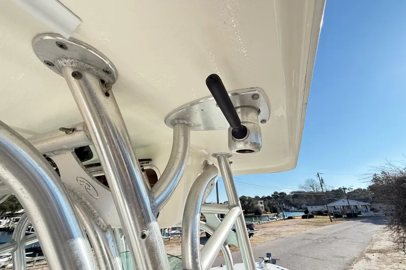 Slide: The Image of 2008 Robalo R240 Center Console boat's T-top structure with rod holders, under clear sky. - 33