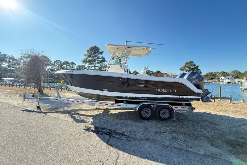 Slide: The Image of 2008 Robalo R240 Center Console boat on trailer, parked near waterfront under clear blue sky. - 4