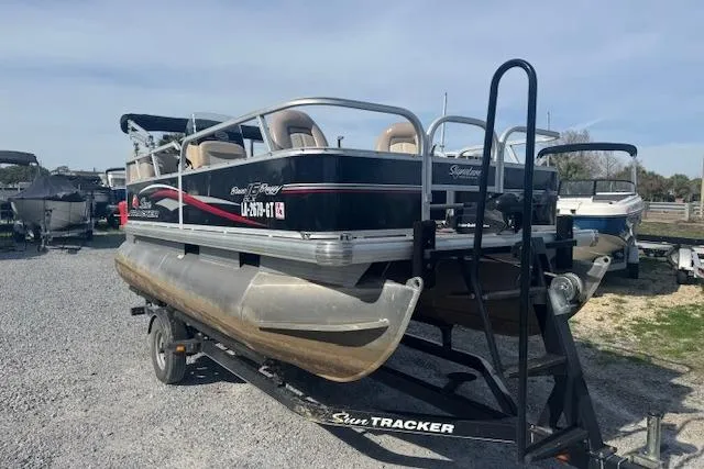 Slide: The Image of 2015 Sun Tracker Bass Buggy 16 DLX pontoon boat on trailer, parked on gravel. - 3