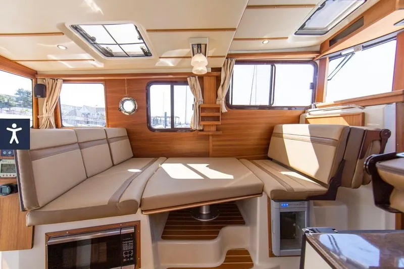 Slide: The Image of 2024 Ranger Tugs R-31 CB interior with beige seating and wood accents. - 14