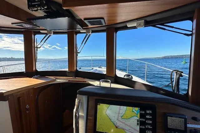 Slide: The Image of 2024 Ranger Tugs R-31 CB interior with navigation display, overlooking serene ocean view. - 15