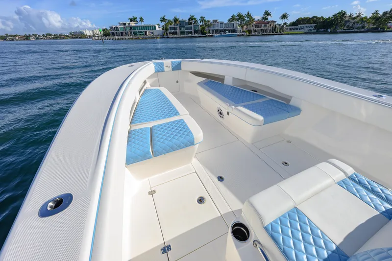 Slide: The Image of 2022 SeaVee 340Z boat with blue seating, cruising near waterfront homes. - 6