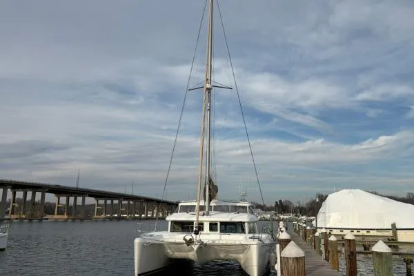 Slide: The Image of 2008 Lagoon 420 catamaran docked at a marina under a cloudy sky. - 3