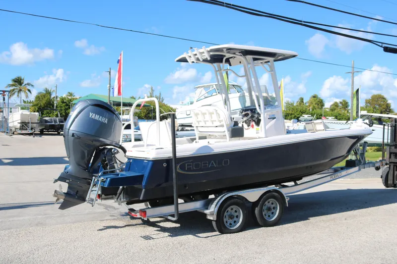 Slide: The Image of 2024 Robalo 226 Cayman boat on trailer with Yamaha engine, parked outdoors. - 2