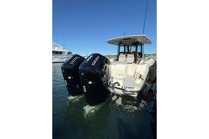 Slide: The Image of 2024 Boston Whaler 360 Outrage with dual outboard engines, docked in calm waters. - 12