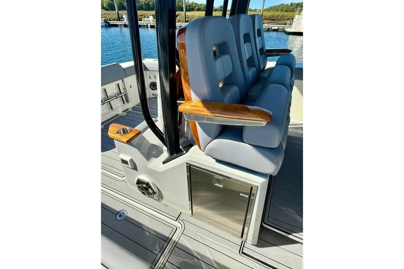 Slide: The Image of 2024 Boston Whaler 360 Outrage interior seating with armrests and storage. - 18