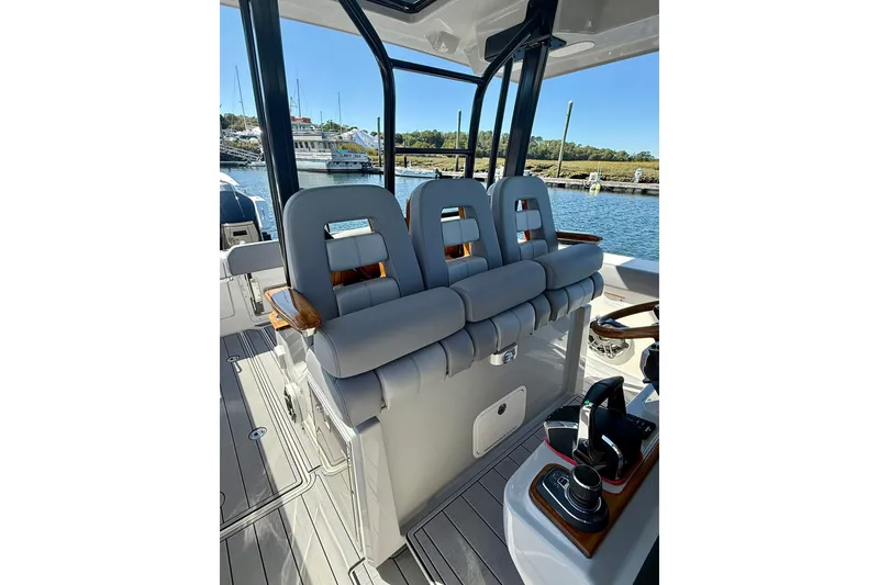 Slide: The Image of 2024 Boston Whaler 360 Outrage boat interior with cushioned seating and control panel. - 19