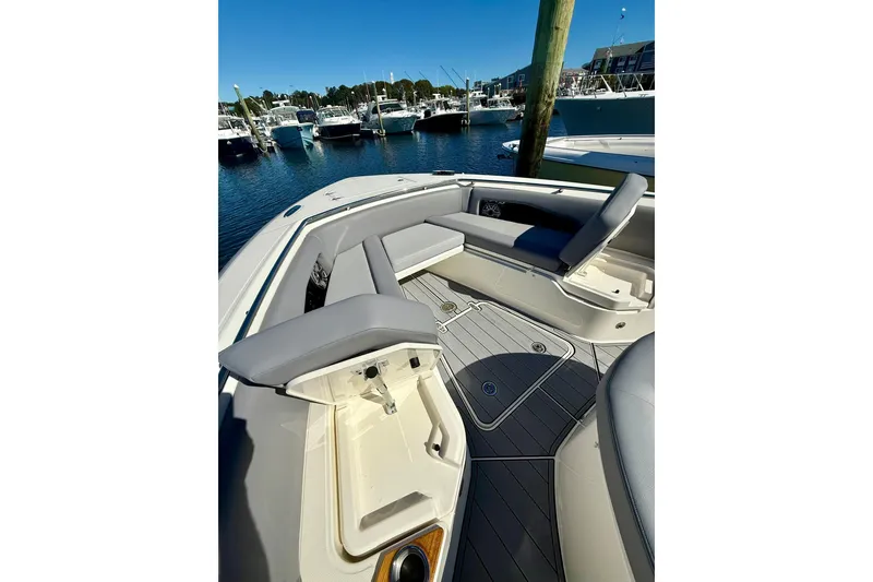 Slide: The Image of 2024 Boston Whaler 360 Outrage boat interior with seating and storage, docked at marina. - 26