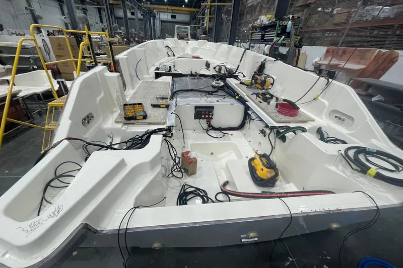 Slide: The Image of 2024 Boston Whaler 360 Outrage under construction in a workshop, showcasing interior wiring and components. - 45