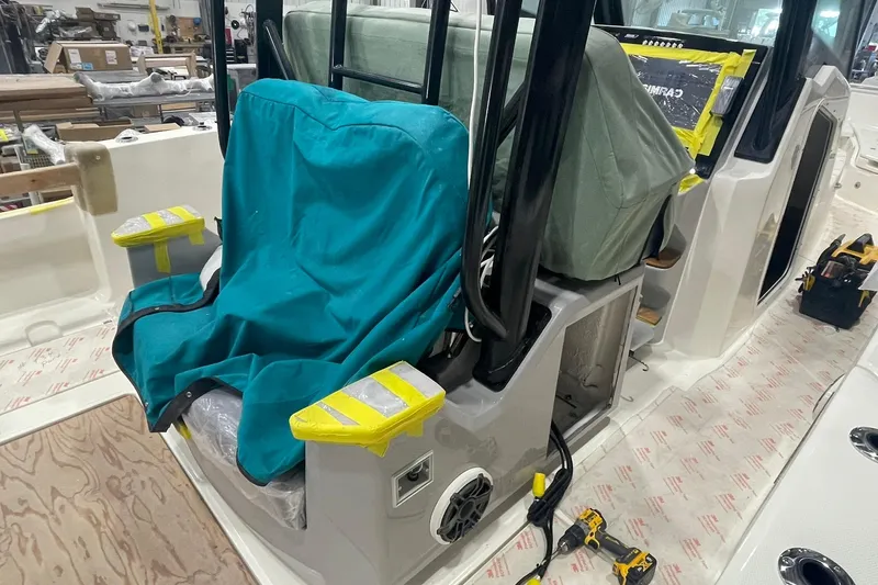 Slide: The Image of 2024 Boston Whaler 360 Outrage interior under construction, featuring covered seating and tools. - 56