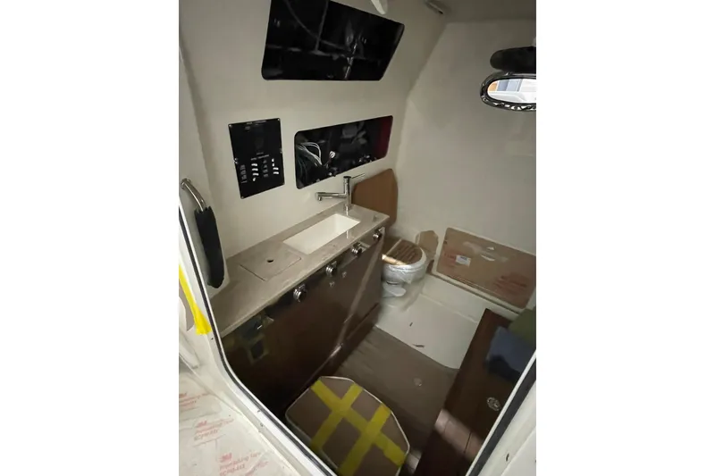 Slide: The Image of 2024 Boston Whaler 360 Outrage cabin interior with sink, toilet, and control panel. - 69