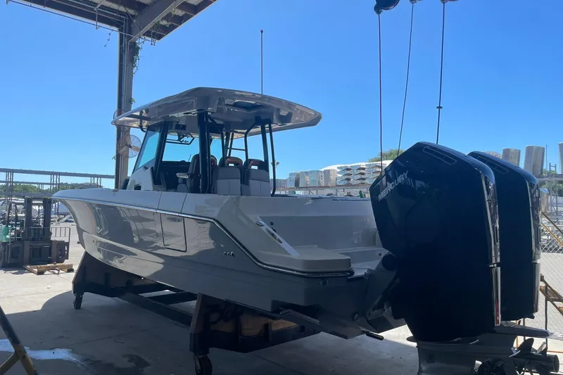 Slide: The Image of 2024 Boston Whaler 360 Outrage boat with dual Mercury engines in a marina setting. - 75