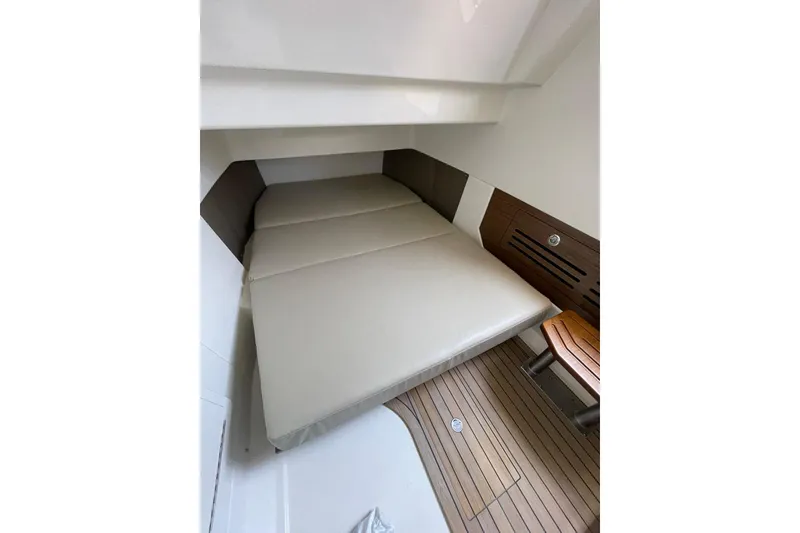Slide: The Image of 2024 Boston Whaler 360 Outrage cabin interior with cushioned bed and wooden flooring. - 80