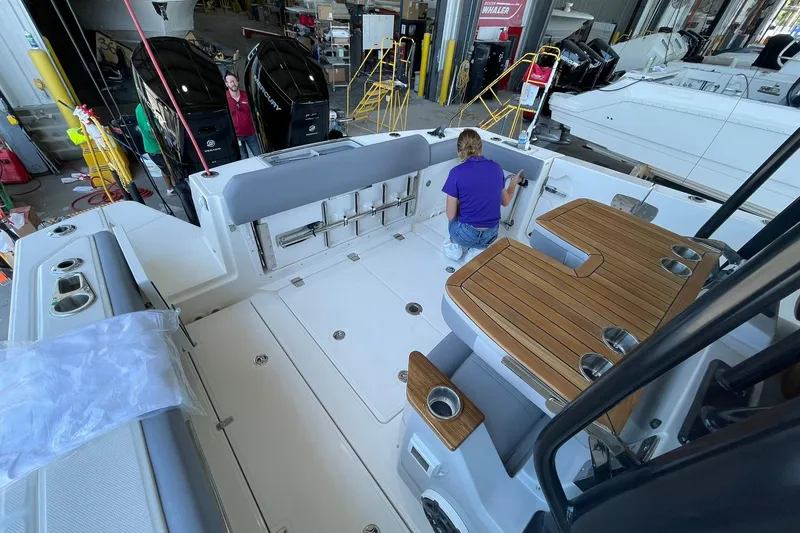 Slide: The Image of 2024 Boston Whaler 360 Outrage boat interior with teak accents and dual Mercury engines. - 83