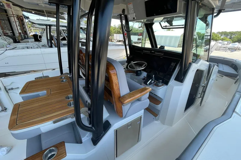 Slide: The Image of 2024 Boston Whaler 360 Outrage interior with helm, seating, and wooden accents. - 84