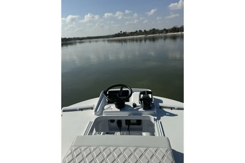 Slide: The Image of 2025 Yellowfin 26 Hybrid boat dashboard with serene lake view. - 28