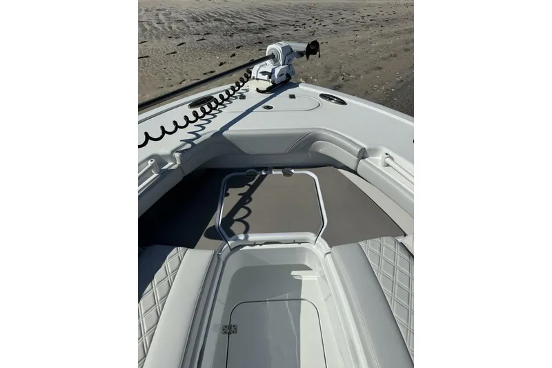 Slide: The Image of 2025 Yellowfin 26 Hybrid boat interior with seating and storage, on sandy beach background. - 5